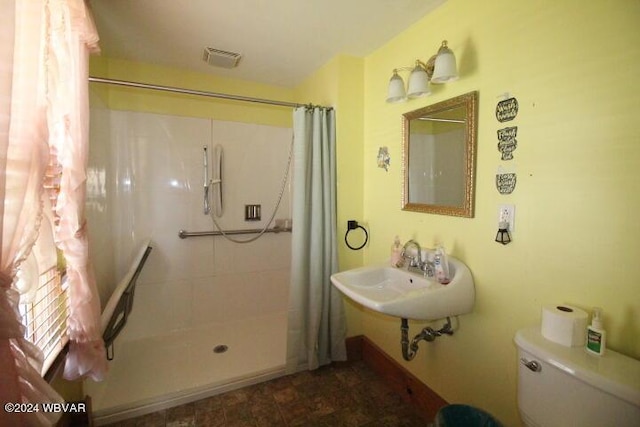 bathroom featuring sink, a shower with shower curtain, and toilet