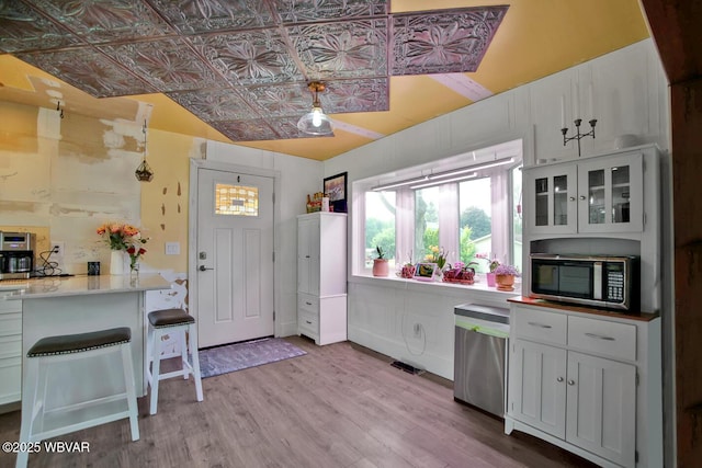 2177 N Williamson Rd, Covington, PA 16917 - kitchen with stainless steel microwave, an ornate ceiling, light wood finished floors, glass insert cabinets, and white cabinets
