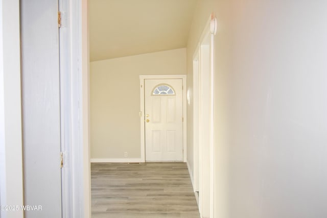 hallway with light hardwood / wood-style floors and lofted ceiling