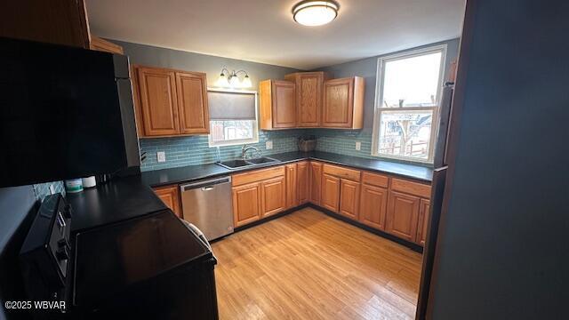 kitchen featuring brown cabinets, decorative backsplash, a sink, light wood-type flooring, and dishwasher