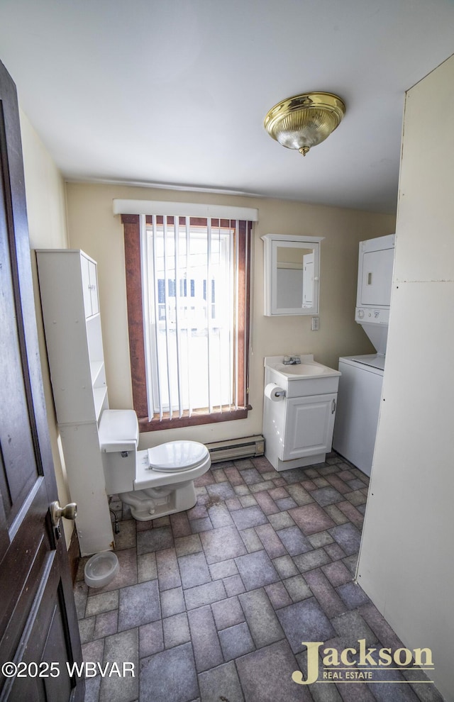 bathroom with stacked washer and dryer, toilet, sink, and a baseboard radiator