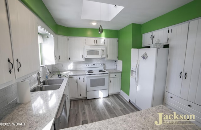 kitchen featuring a skylight, white cabinetry, white appliances, light wood-type flooring, and sink