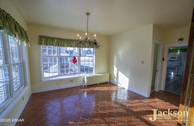 unfurnished dining area featuring dark tile patterned floors, radiator, and plenty of natural light