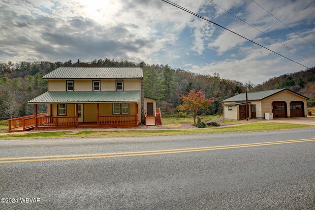 view of front of home with a porch, a garage, and an outbuilding