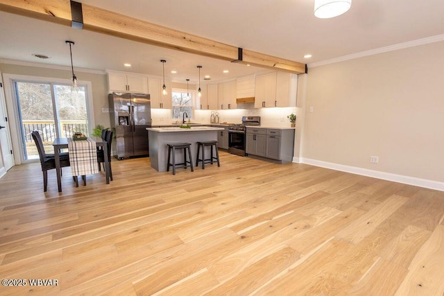 kitchen with white cabinets, a kitchen island, stainless steel appliances, and decorative light fixtures