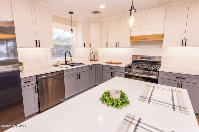 kitchen with a sink, stainless steel appliances, light countertops, and gray cabinetry