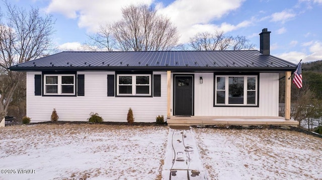 view of front of house featuring a chimney and metal roof