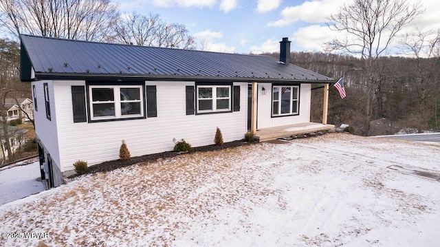 view of front of house featuring metal roof and a chimney