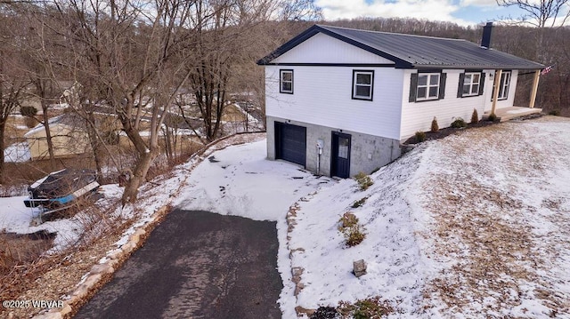 view of snowy exterior with a garage and metal roof