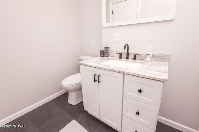 half bathroom featuring toilet, tile patterned flooring, vanity, and baseboards