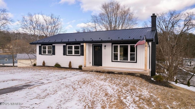 ranch-style house featuring metal roof and a chimney