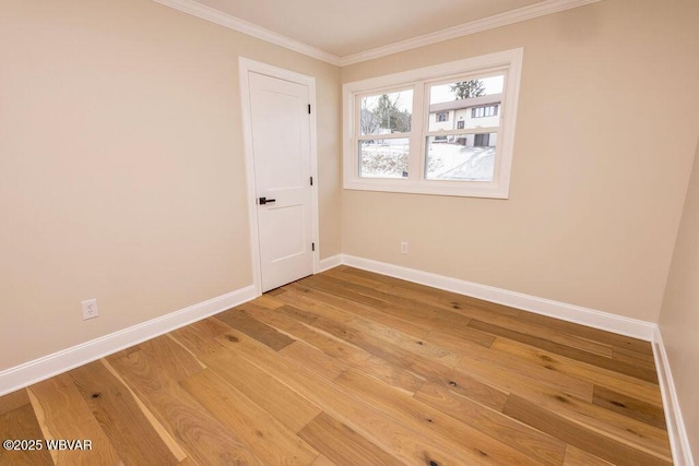 empty room featuring crown molding, baseboards, and wood finished floors