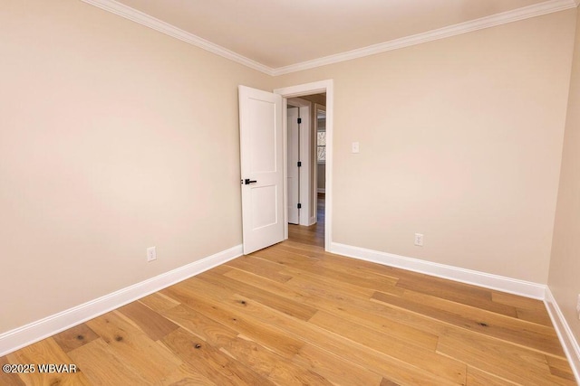 spare room featuring crown molding, baseboards, and wood finished floors