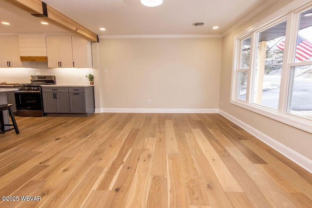 kitchen featuring visible vents, gray cabinets, light countertops, stainless steel range with gas cooktop, and white cabinetry