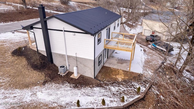 view of snowy exterior with a deck and cooling unit