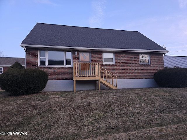 rear view of house with a lawn, brick siding, and a shingled roof