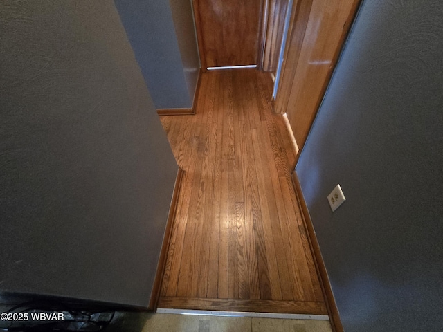 corridor featuring baseboards and wood finished floors