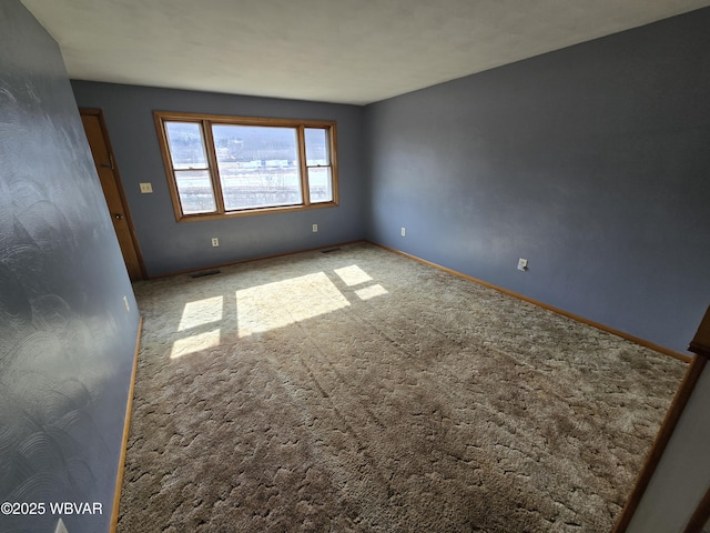 carpeted spare room featuring visible vents and baseboards