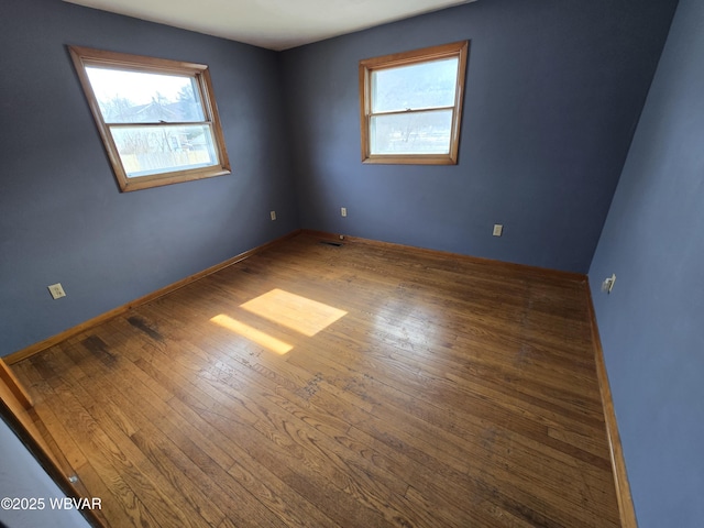 unfurnished room featuring visible vents, baseboards, and hardwood / wood-style floors