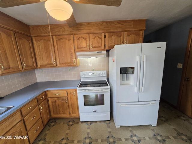 kitchen featuring white appliances, backsplash, brown cabinetry, and under cabinet range hood