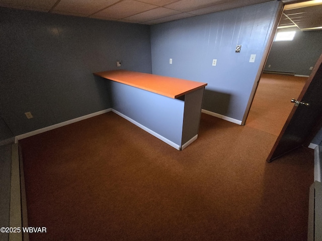 unfurnished office featuring a bar, a paneled ceiling, dark colored carpet, and baseboards