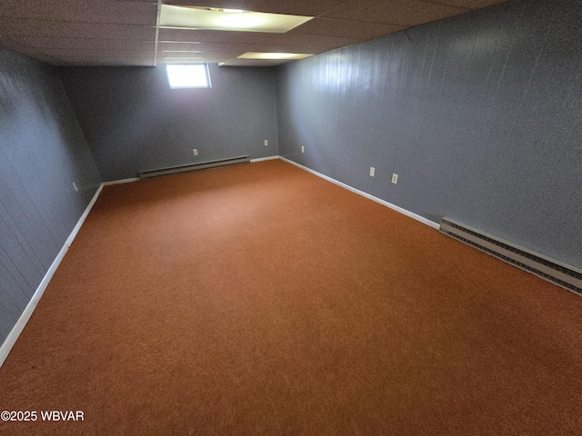 basement with a drop ceiling, baseboards, a baseboard heating unit, and carpet