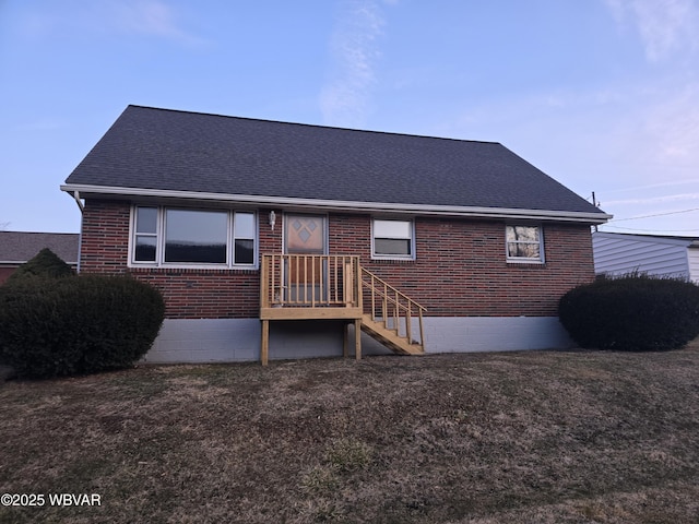 rear view of property featuring a yard, brick siding, and a shingled roof