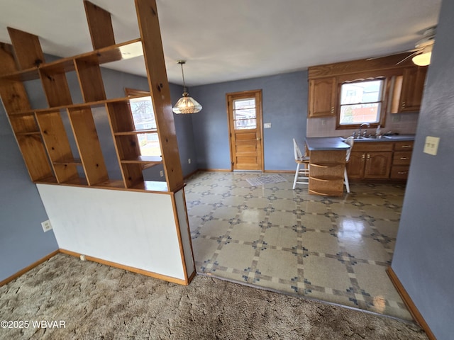 kitchen with a sink, decorative backsplash, baseboards, and brown cabinetry