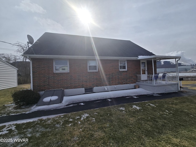 back of property featuring a yard and brick siding