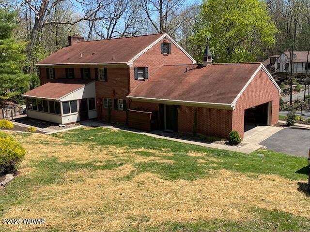 1550 Campbell St, Williamsport, PA 17701 - view of front of property with a garage, a chimney, a sunroom, brick siding, and driveway