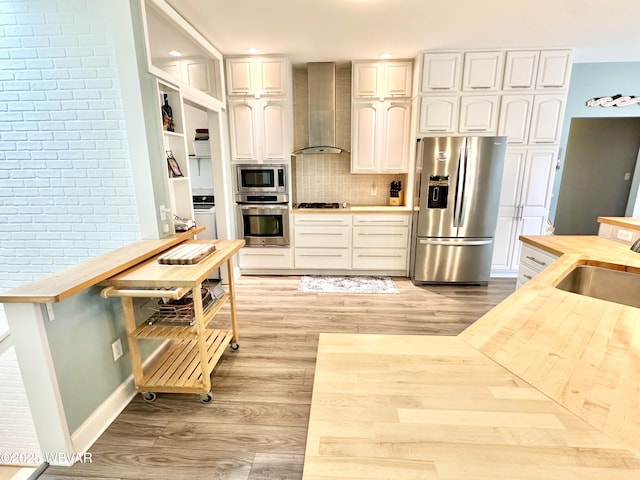 2035 Woodland Rd, Montoursville, PA 17754 - kitchen with appliances with stainless steel finishes, wall chimney exhaust hood, butcher block counters, a sink, and light wood-style floors