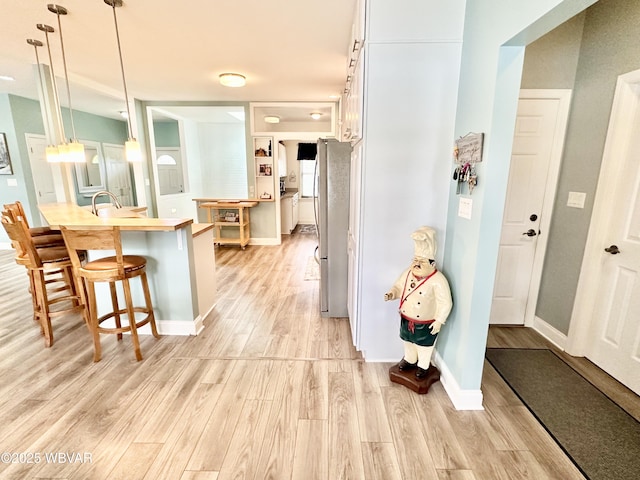 2035 Woodland Rd, Montoursville, PA 17754 - kitchen featuring freestanding refrigerator, a kitchen bar, light wood-type flooring, and decorative light fixtures