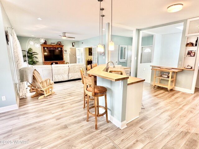 2035 Woodland Rd, Montoursville, PA 17754 - kitchen with butcher block countertops, light wood-style flooring, a ceiling fan, a sink, and a breakfast bar