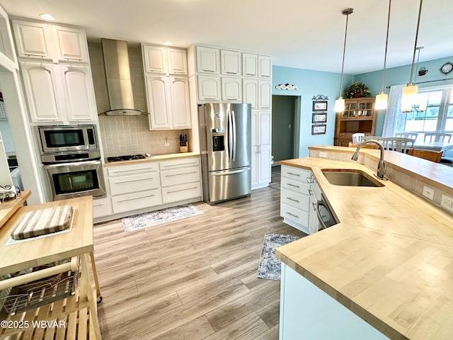 2035 Woodland Rd, Montoursville, PA 17754 - kitchen with appliances with stainless steel finishes, wall chimney exhaust hood, a sink, butcher block countertops, and recessed lighting