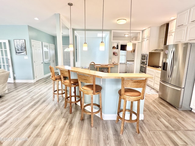 2035 Woodland Rd, Montoursville, PA 17754 - kitchen featuring stainless steel appliances, washer and clothes dryer, a kitchen breakfast bar, light wood-style flooring, and baseboards