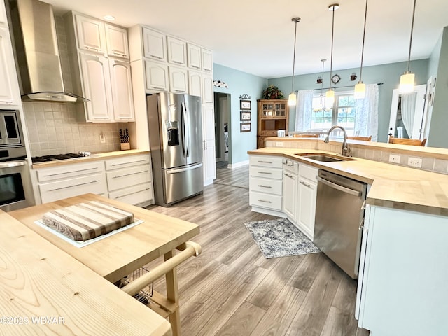 2035 Woodland Rd, Montoursville, PA 17754 - kitchen with appliances with stainless steel finishes, wall chimney range hood, a sink, backsplash, and light wood-type flooring