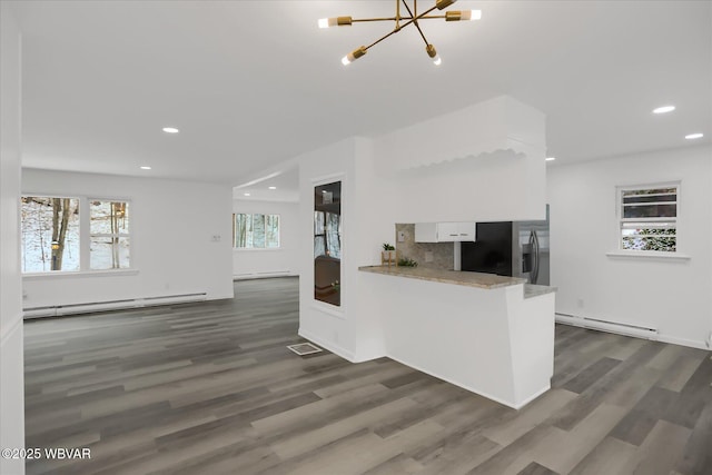 kitchen with white cabinetry, a baseboard heating unit, kitchen peninsula, dark hardwood / wood-style flooring, and stainless steel fridge