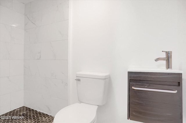 bathroom with vanity, toilet, and a tile shower