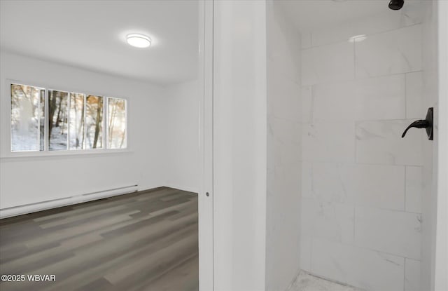 bathroom with a shower, hardwood / wood-style floors, and a baseboard heating unit