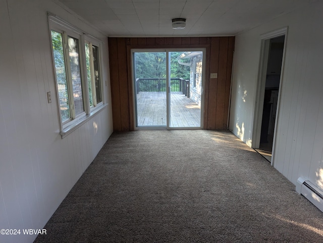 unfurnished room featuring carpet floors, baseboard heating, and wooden walls