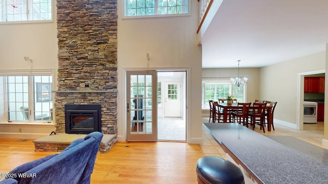 2180 Stopper Dr, Montoursville, PA 17754 - living area featuring wood finished floors, a stone fireplace, a chandelier, a towering ceiling, and washer / clothes dryer