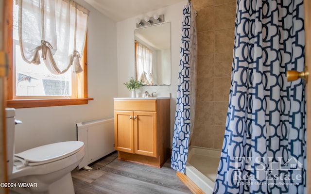 bathroom featuring radiator, wood-type flooring, toilet, vanity, and a shower with shower curtain