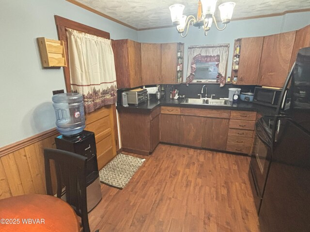 145 Gulick St, Blossburg, PA 16912 - kitchen with a wainscoted wall, brown cabinets, wood finished floors, a notable chandelier, and a sink
