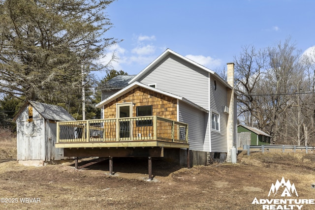 rear view of property with a deck, a storage shed, an outbuilding, and a chimney