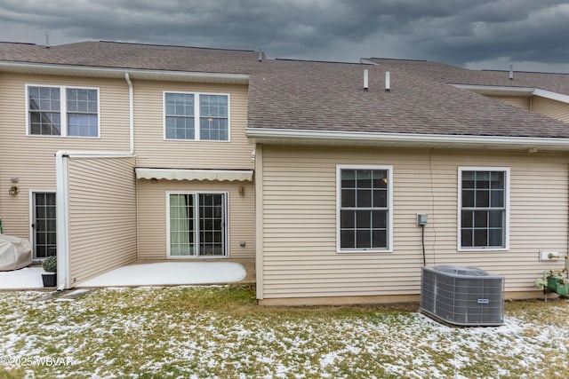 snow covered property with a patio and central AC