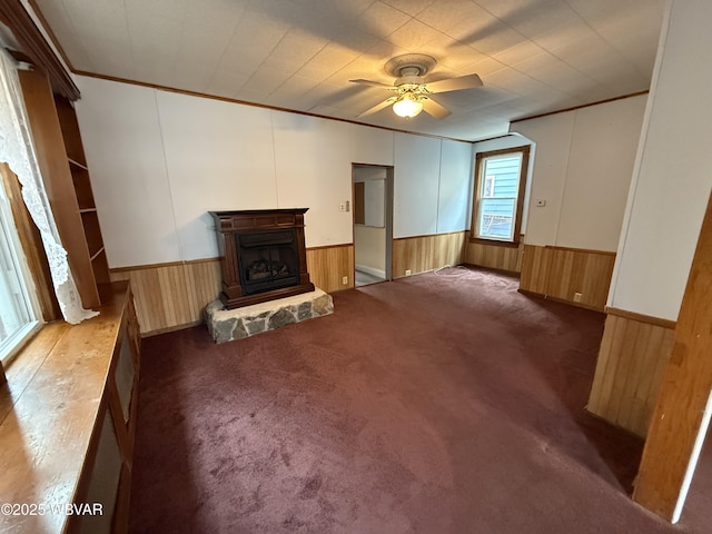 unfurnished living room featuring crown molding, ceiling fan, a fireplace, and carpet