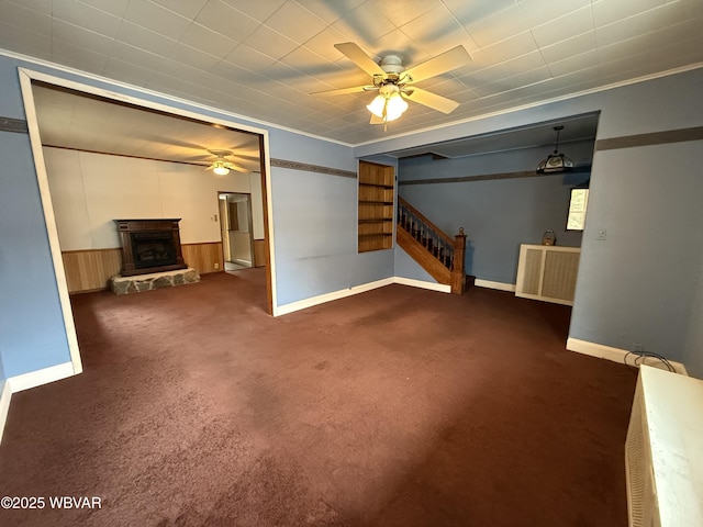 interior space with dark colored carpet, crown molding, ceiling fan, and a fireplace