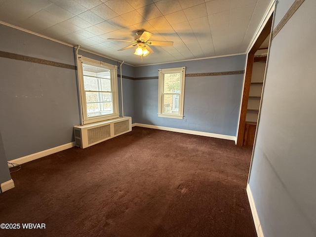 spare room with ceiling fan, radiator heating unit, and dark colored carpet