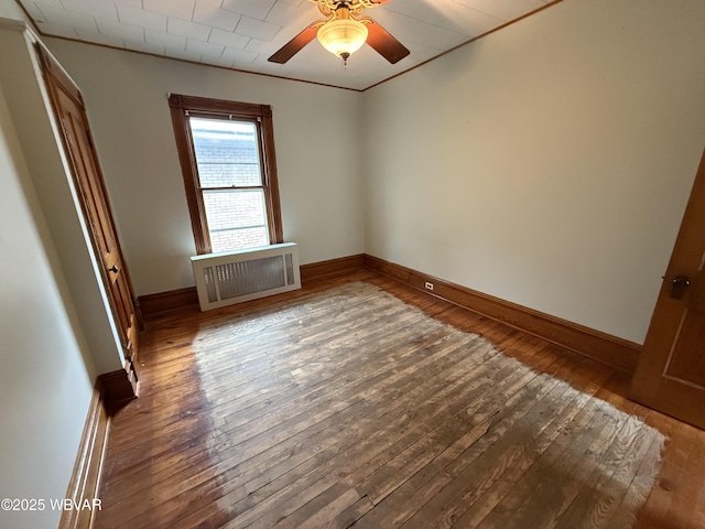 unfurnished room with ceiling fan, ornamental molding, radiator heating unit, and dark hardwood / wood-style flooring