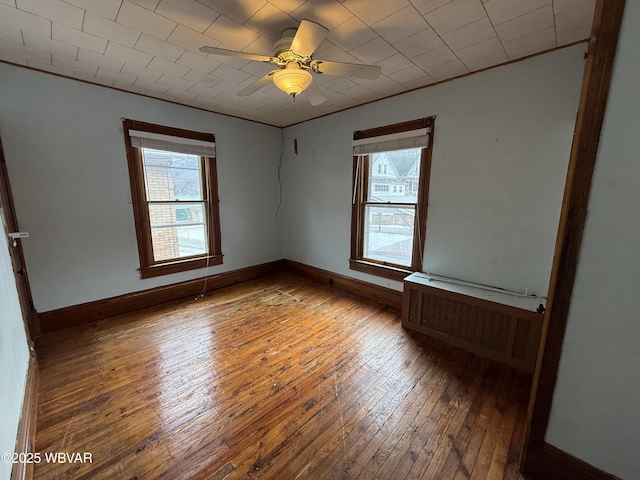 spare room featuring a wealth of natural light, radiator, hardwood / wood-style floors, and ceiling fan